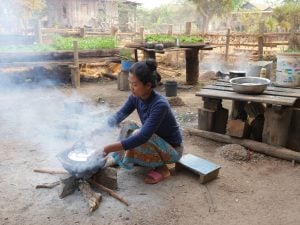 woman squatting over pot on stone stove