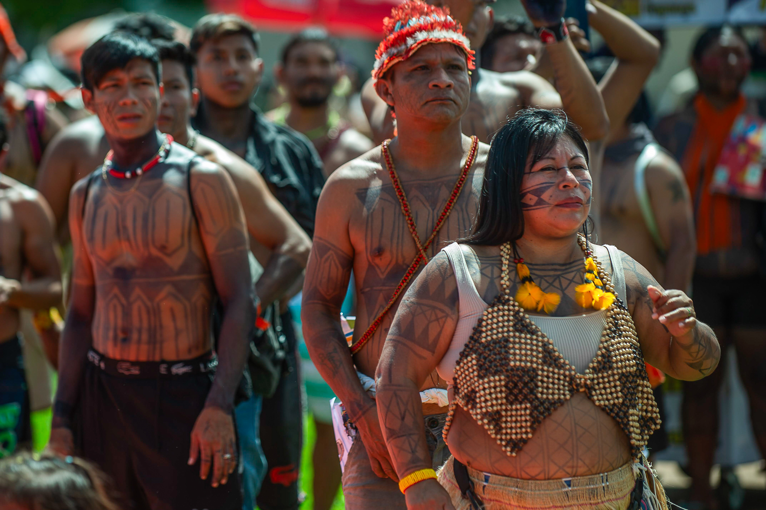 Indigenous people with traditional body paint and jewelry standing in a group