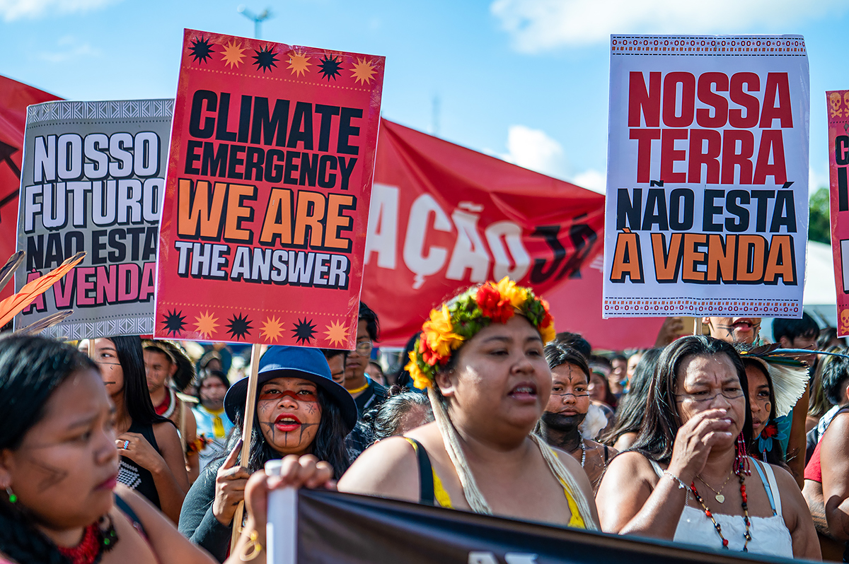 A diverse group of individuals holding protest signs and banners