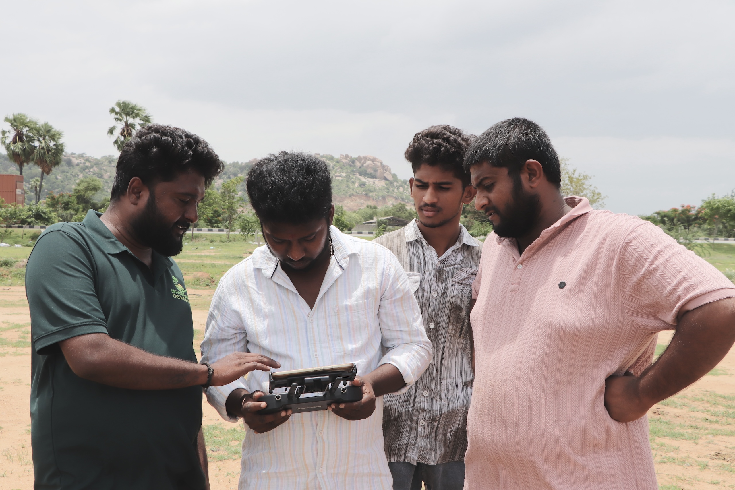 four men looking at drone controller