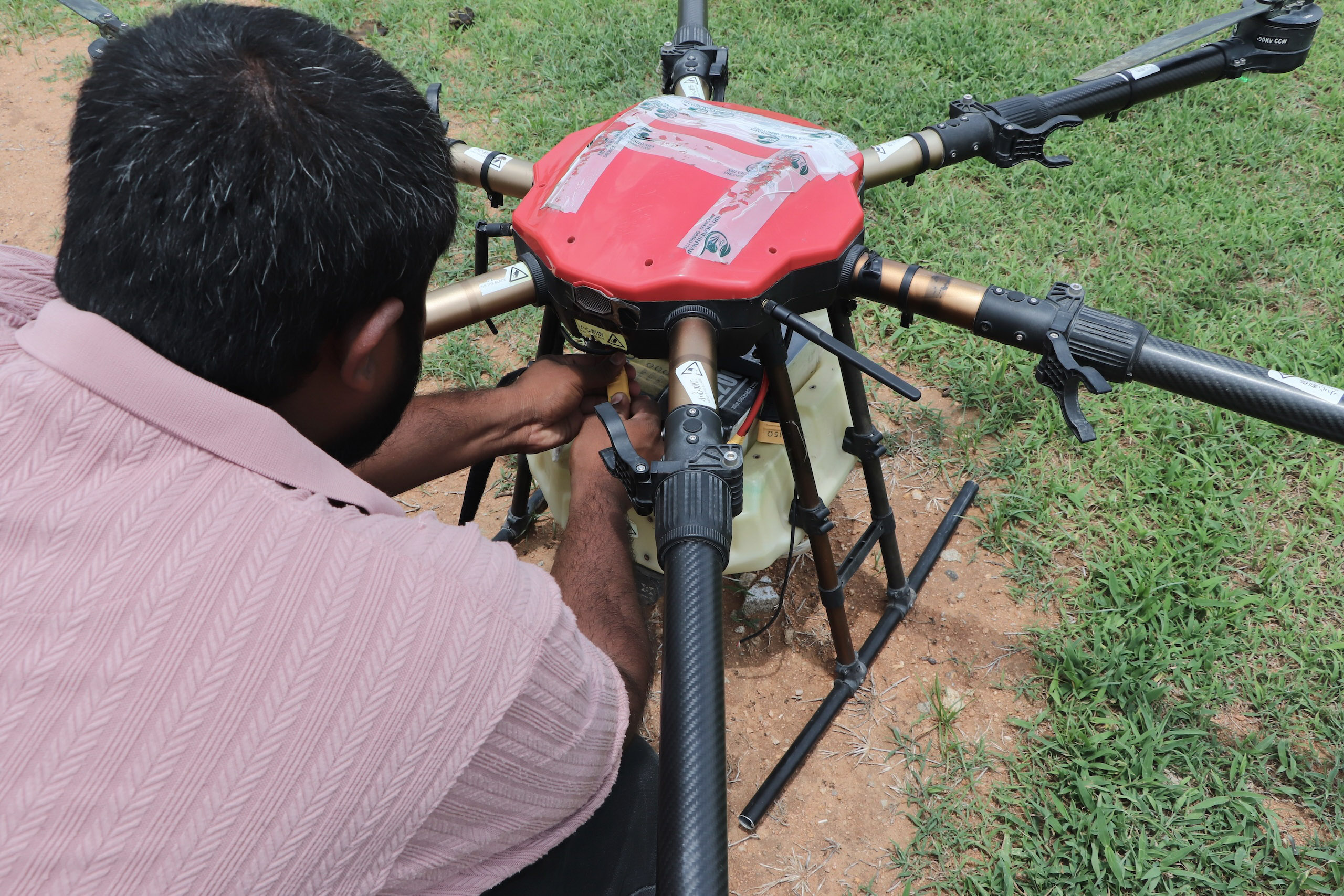 <p>Shiva Reddy attaches a battery to an agricultural drone during a training session in Nalgonda, Telangana. Climate change and rising labour costs have led younger farmers like him to experiment with agri-tech for crop management (Image: Almaas Masood)</p>