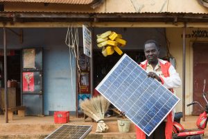 Man holds solar panel in front of shops