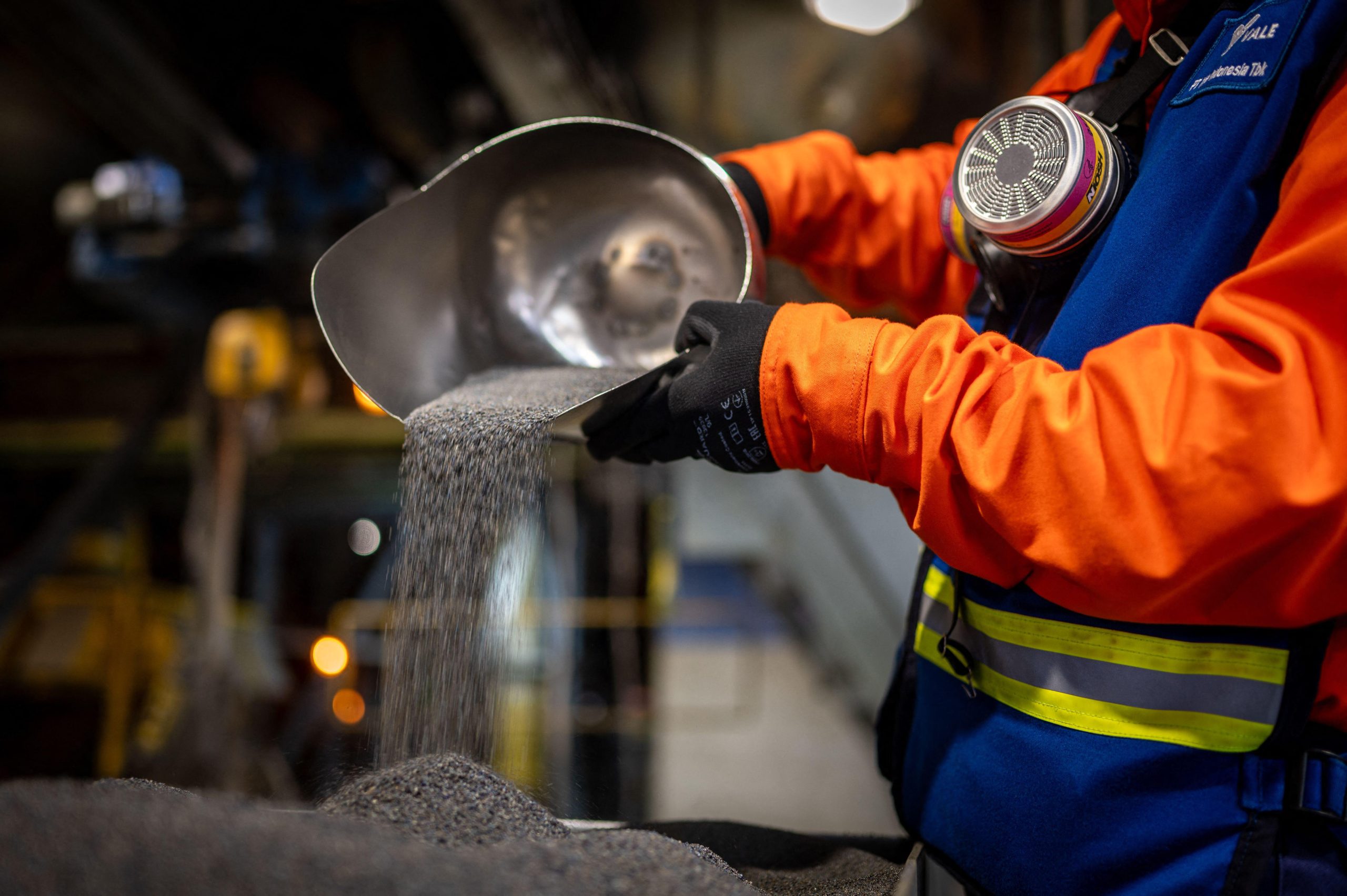 person in protective gear pouring nickel ore onto pile
