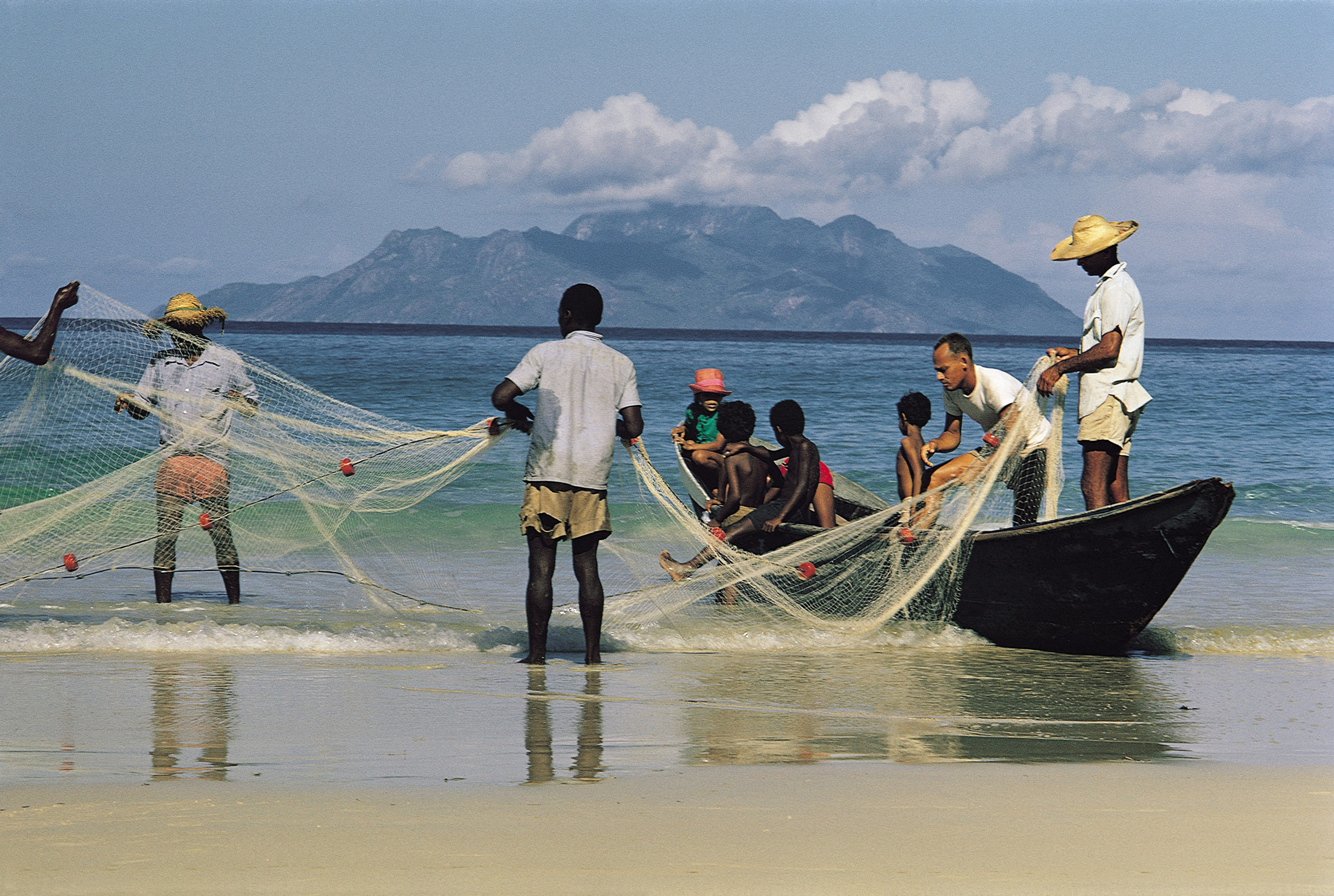 fishers on beach pulling net in from water