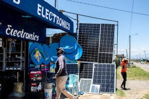 An electronics shop selling solar panels and other products, with a man walking past