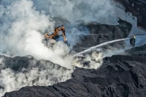Workers sprinkle water on coal at a coal yard