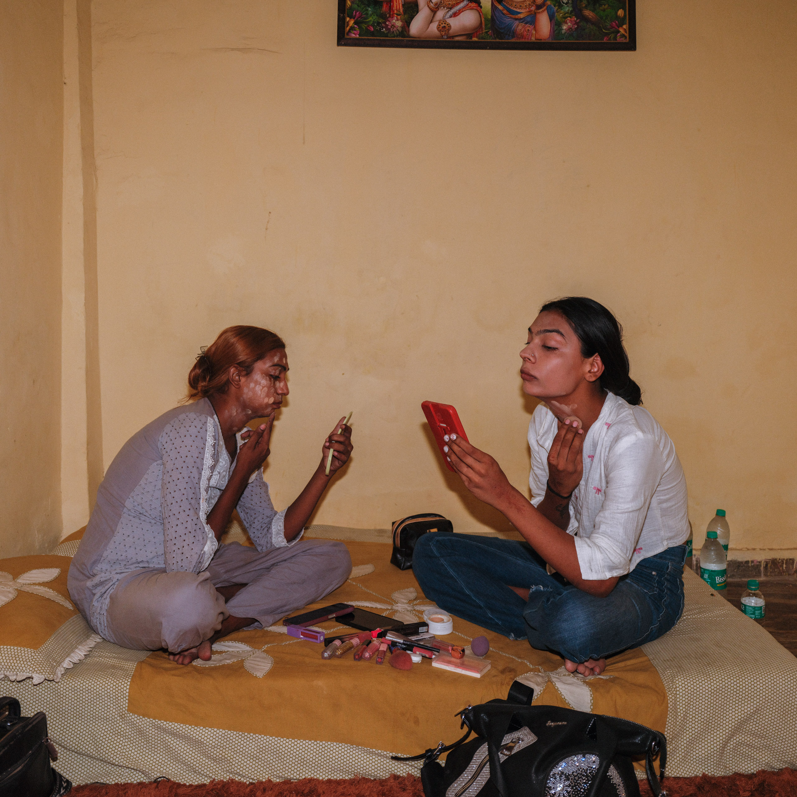 two women sitting cross legged and applying makeup
