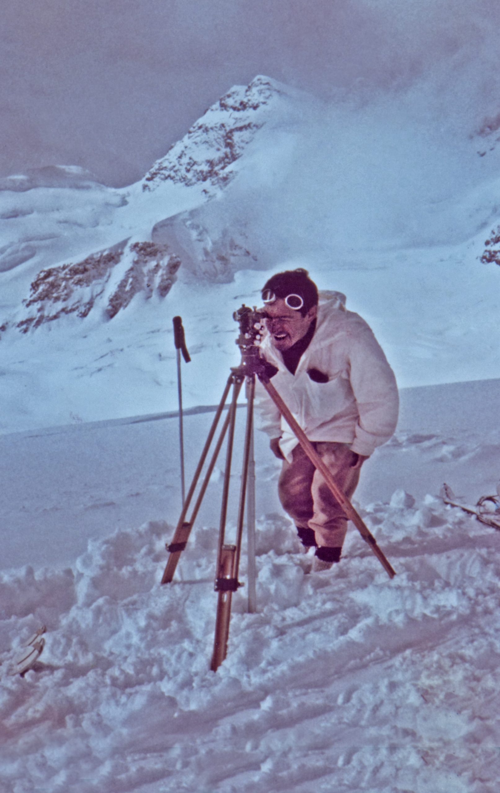 man carrying out topographical survey in snowy region