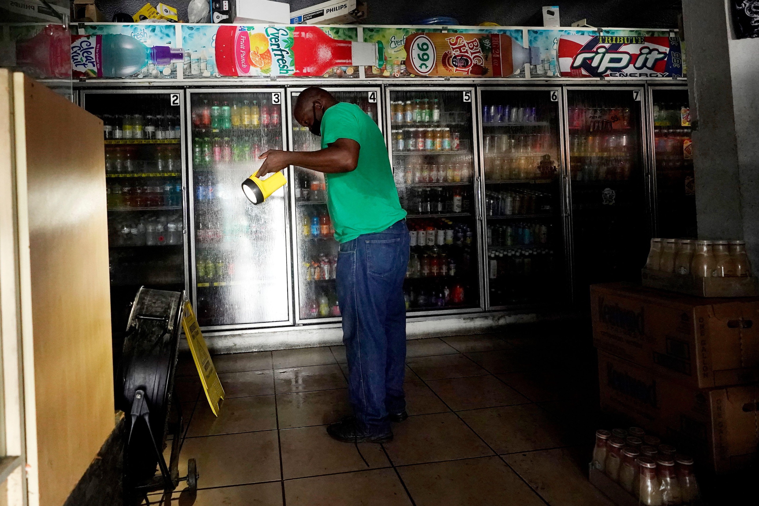a man uses a torch to navigate a shop during a power cut 