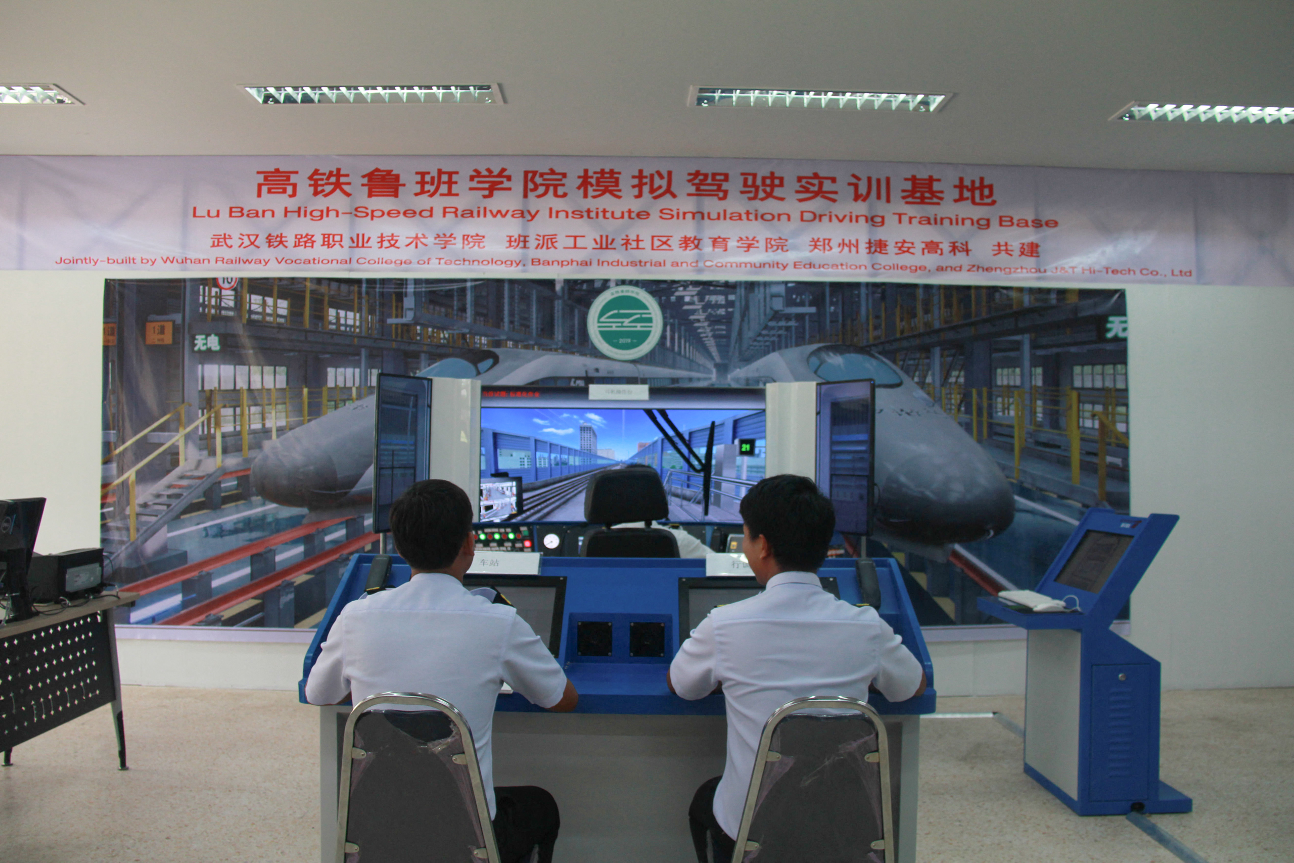 two men seated in front of train driving simulator