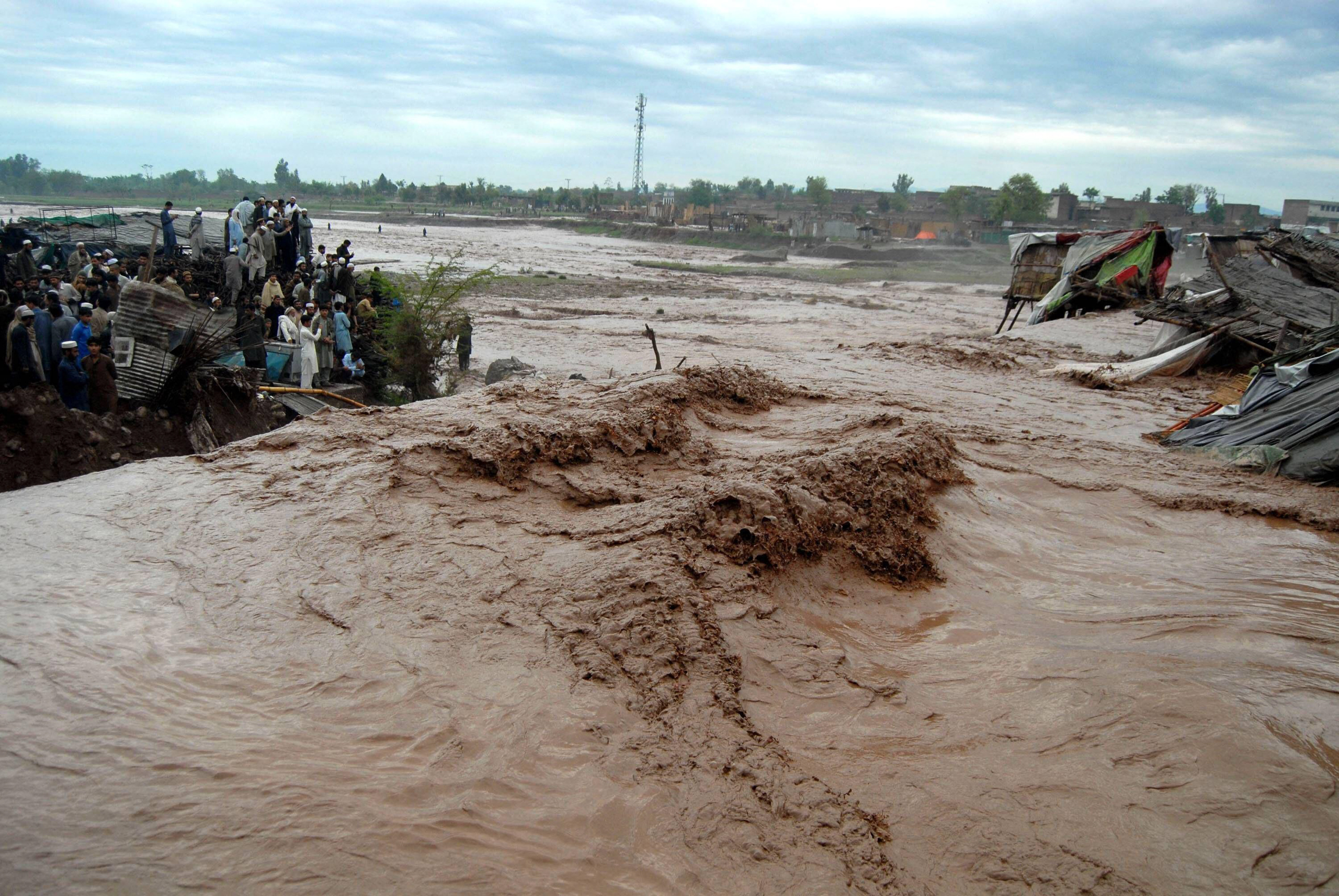 people stand on high ground near muddy flood