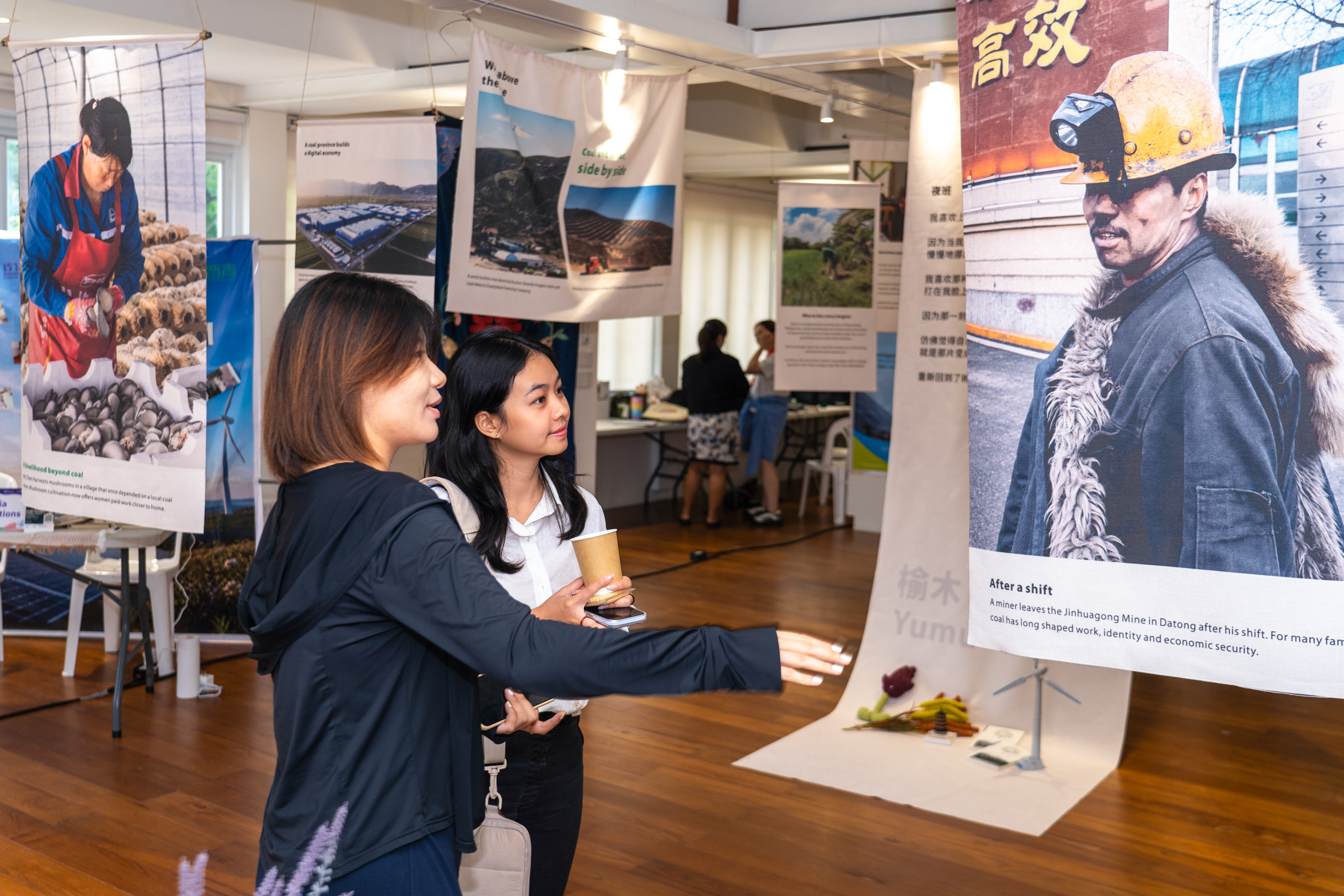 Two young women look at a photo of coal miner in an exhibition