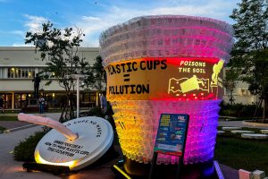 A sculpture made of plastic cups with colourful lights, in the garden of a low-rise building