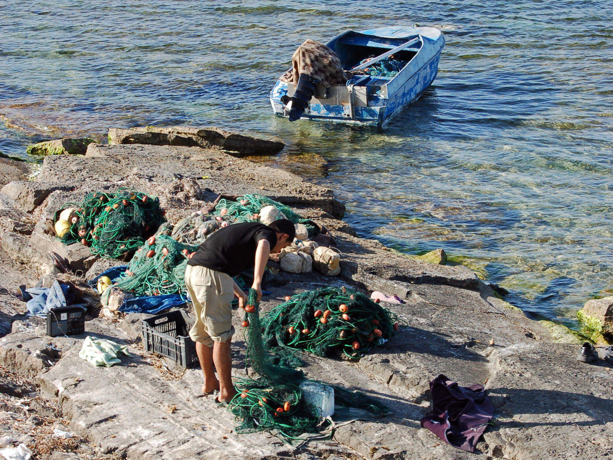 fisherman checking nets on rock shore