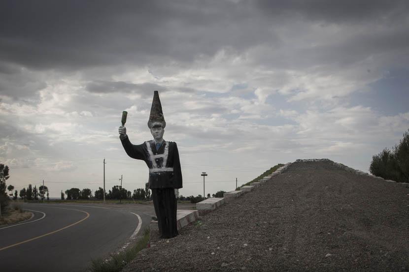 A statue of a police man with a cone on his head and a beer bottle in his hand on the road leading to 404 City [image by Xu Haifeng/Sixth Tone]
