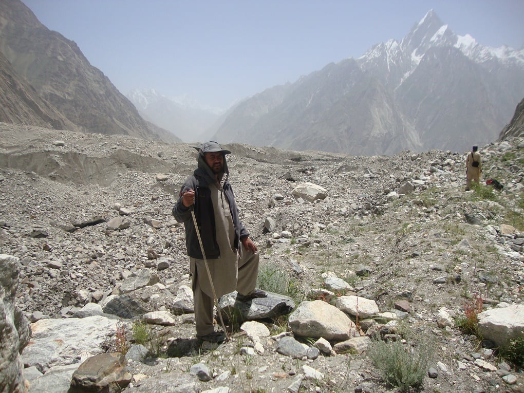 Member of monitoring team standing in front of a Debris-covered Glacier [image courtesy: WAPDA]