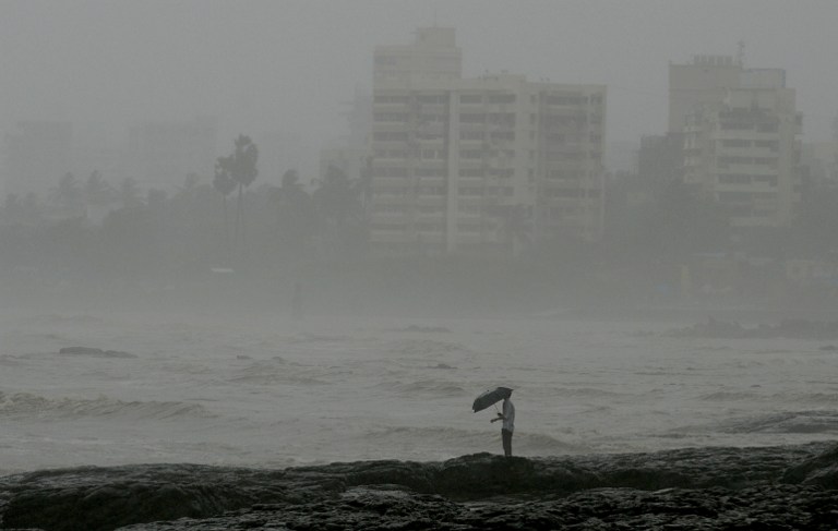 An Indian man stands by the sea front during heavy rain showers in Mumbai on June 18, 2013. [AFP photo / Punit Paranjpe]